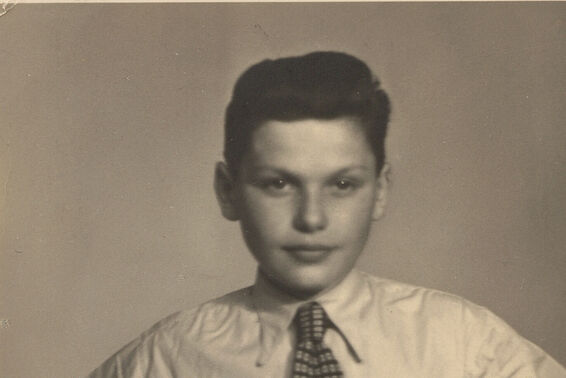 Altes schwarz-weißes Foto von einem Jungen mit Krawatte, die Hände in die Hüften gestützt.