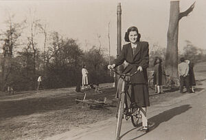 Schwarz-weißes Foto von lächelnder Frau auf einem Fahrrad in einem Park.