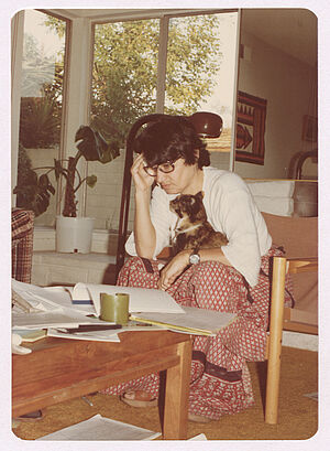 Woman with black hair sitting in a living room with a cat on her lap