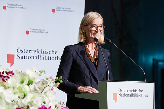 Lächelnde Frau an einem Rednerpult.