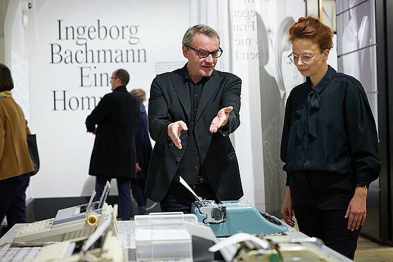 Ein Mann zeigt auf eine Schreibmaschine, eine Frau steht neben ihm.