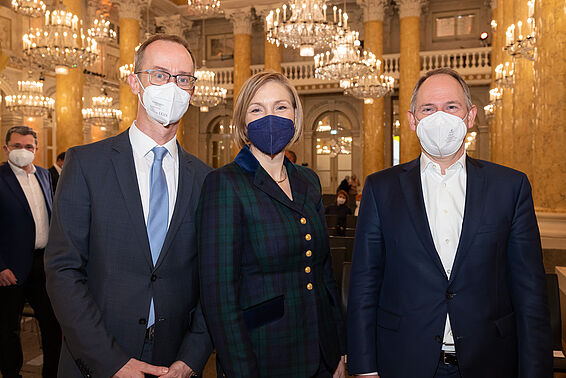 Zwei Männer und eine Frau in eleganter Kleidung