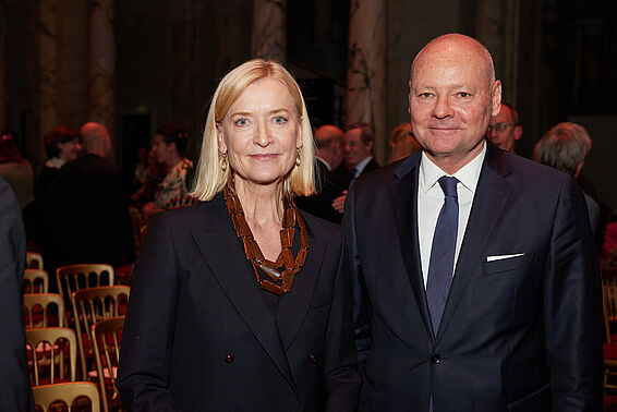 Eine Frau und ein Mann im Anzug posieren.