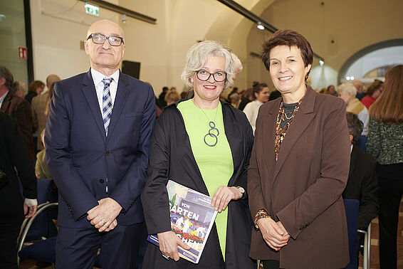 Mann in blauen Anzug mit 2 elegant gekleideten Frauen