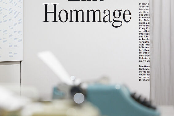 Schreibmaschinen auf einem Tisch, im Hintergrund Schrift an der Wand.