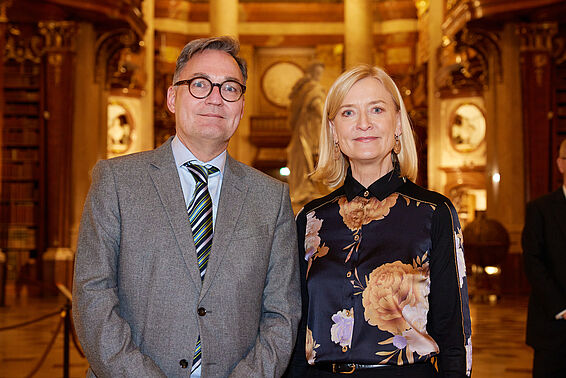 Eine Mann im Anzug und eine blonde Frau im Prunksaal