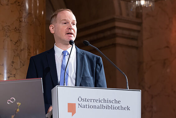 Mann im Anzug steht an einem Rednerpult