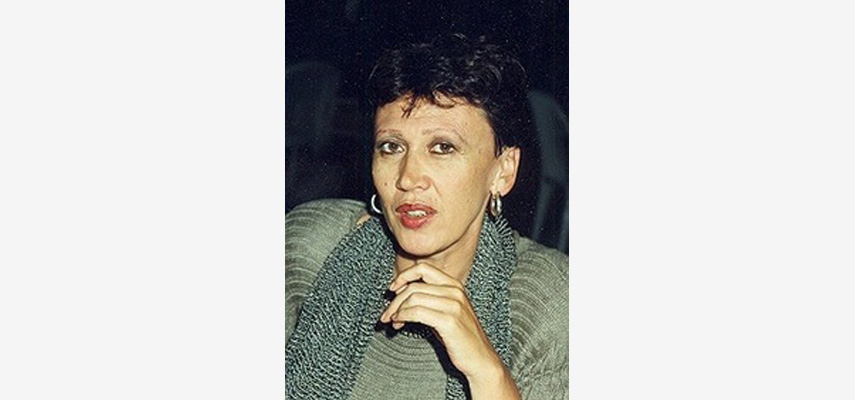 Frau mit dunklen Haaren, Ohrringen, grünem Pullover