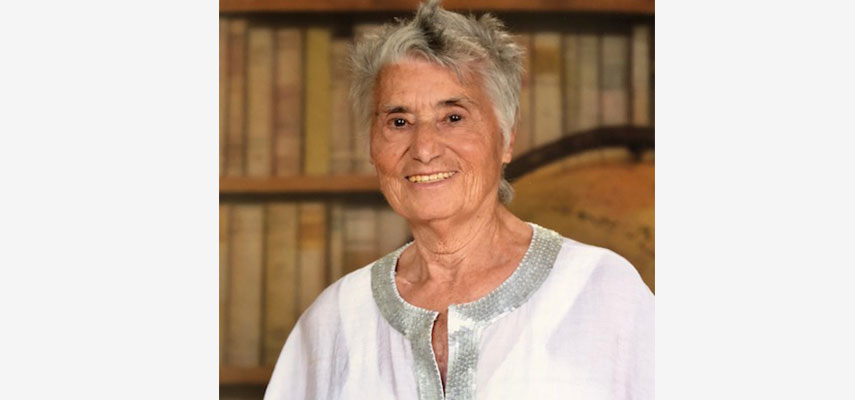 Porträtfoto Frau mit kurzen, grauen Haaren vor Bücherregal