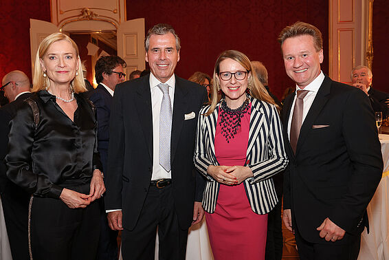 Zwei Frauen und zwei Männer in eleganter Kleidung posieren auf einem Fest