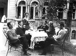 Ludwig Wittgenstein sitzt mit seiner Familie an einem Tisch in einem Garten bei Kaffee und Kuchen, schwarz-weiß