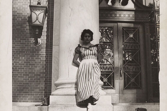 Woman in striped dress leaning against a pillar
