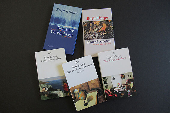 Five thin books, arranged on a dark surface