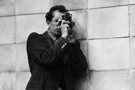 Mann lenht an Mauer und fotografiert