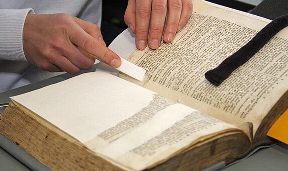Person liest in einem aufgeschlagenen Buch.
