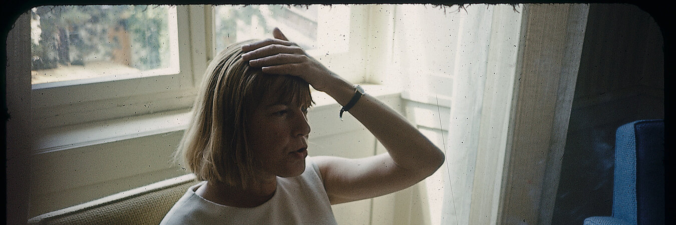 Ingeborg Bachmann auf einem fauteuil sitzend, die linke Hand an die Stirn gelegt