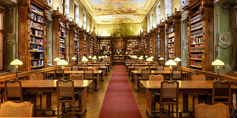 Barocker Lesesaal mit alten Bücherregalen, himmischem Deckenfresko und rotem Teppich