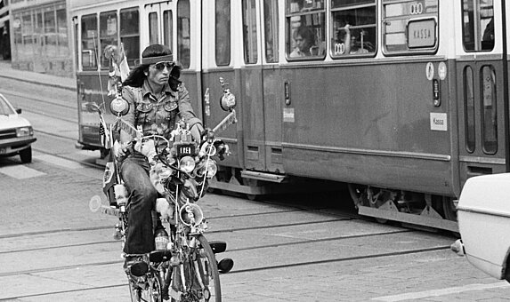 Schwarz-weißes Foto von Person auf Fahrrad neben Straßenbahn.