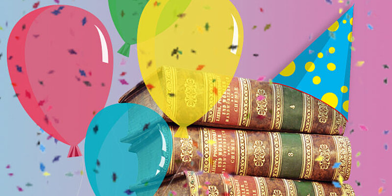 Foto von einem Stapel alter Bücher mit Partyhut und Luftballons