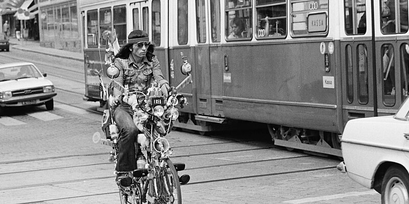 Schwarz-weißes Foto von Person auf Fahrrad neben Straßenbahn.