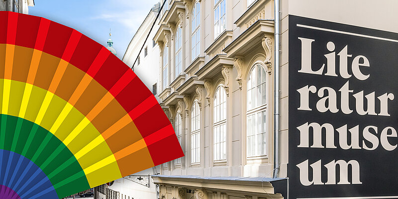 Foto von weißem Altstadt-Gebäude mit Fächer in Regenbogenfarben.