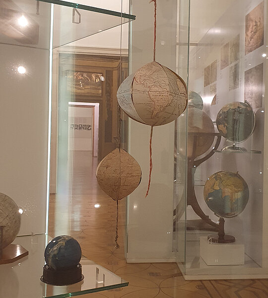 Faltgloben ausgestellt in einer Glasvitrine. 