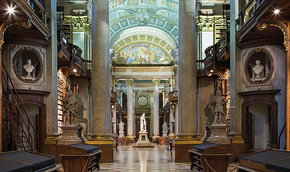 Foto von Marmorsaal mit Statue und Bücherregalen sowie Deckenfresko.