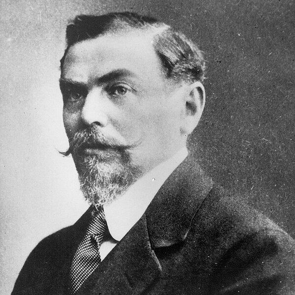 Schwarzweiß-Portrait von Alfred Hermann Fried mit Zwirbelbart und Anzug