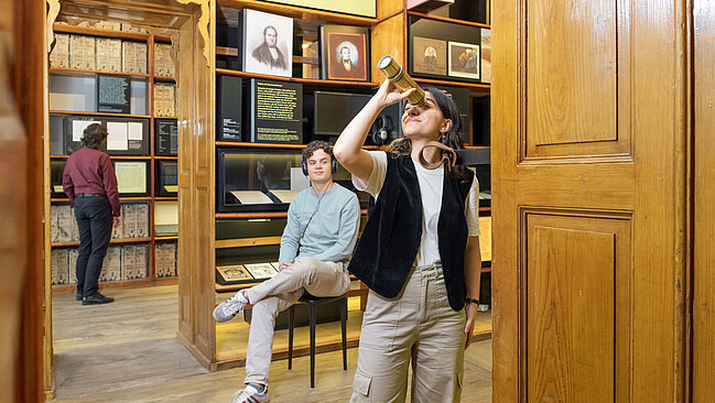 Personen in einem Museum mit alten Bücherregalen