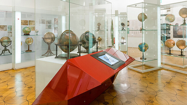 Globen in Vitrinen in einem Ausstellungsraum