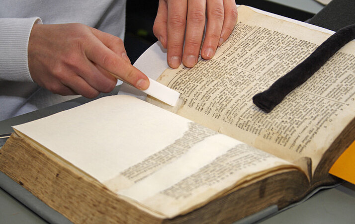 Person liest in einem aufgeschlagenen Buch.