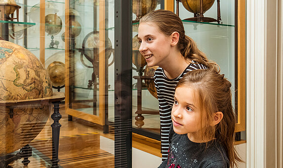Besucherinnen bewundern einen historischen Globus
