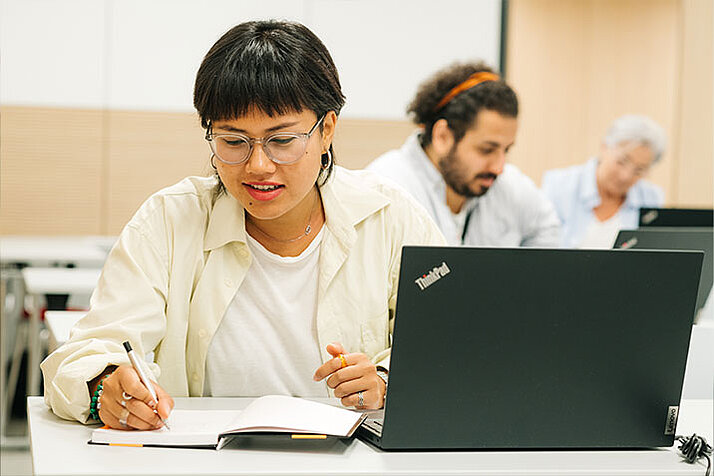 Eine Frau arbeitet an einem Laptop in einem Schulungsraum der Österreichischen Nationalbibliothek.
