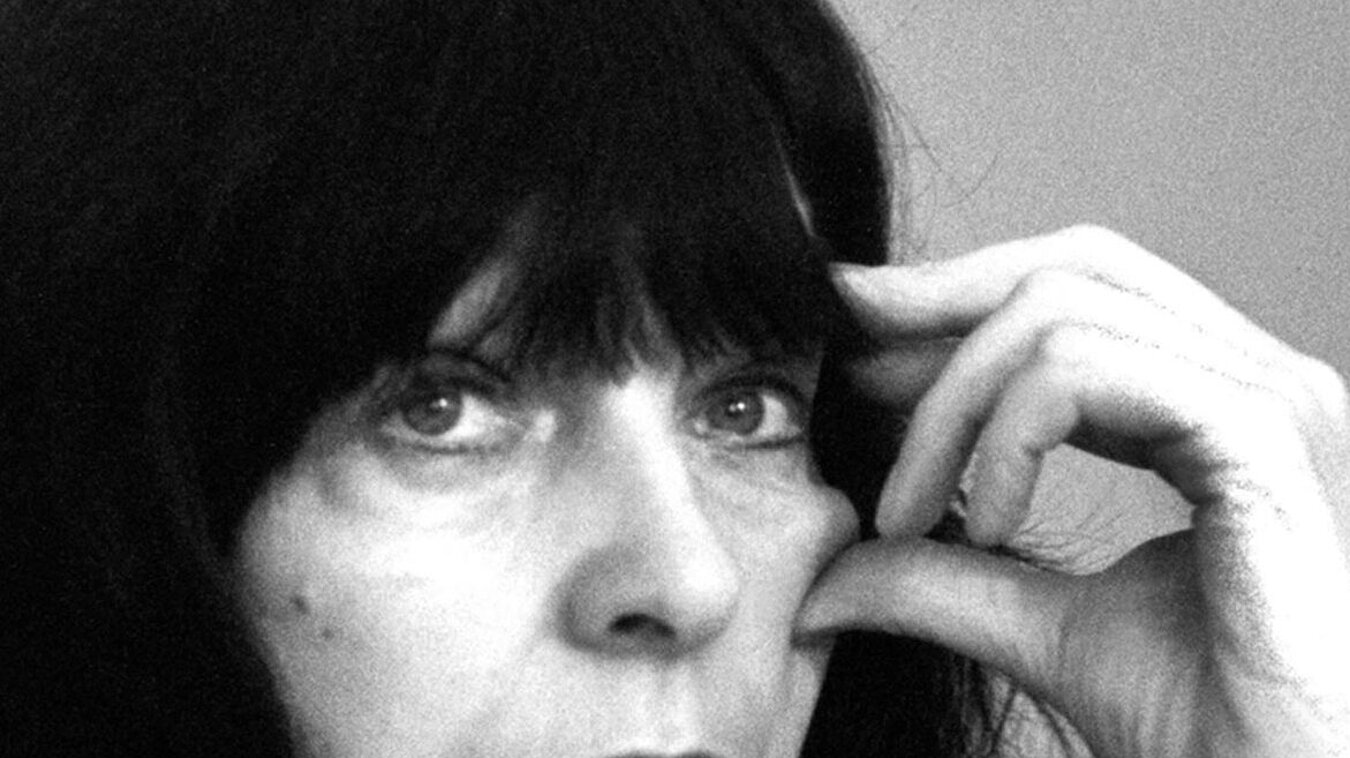 Schwarz-weißes Foto von Person mit langen schwarzen Haaren, die die Hand an das Gesicht hält.