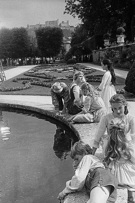 Foto von Menschen vor einem Teich mit Bäumen und einer Burg im Hintergrund.