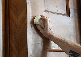 Person schleift das Holz auf der Wand.