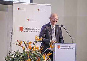 Person auf Bühne spricht in Mikro.