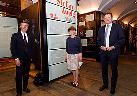 Drei Personen in eleganter Kleidung stehen im Literaturmuseum. 