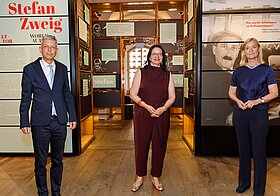 Drei Personen stehen im Literaturmuseum und lächeln in die Kamera.