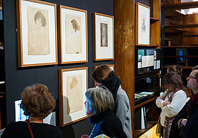 BesucherInnen im Literaturmuseum betrachten eingerahmte Zeichnungen.