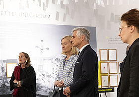 Vier Personen neben Vitrine in Ausstellung.