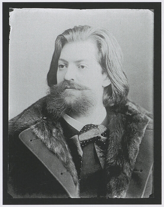 Altes Foto von Mann mit langen Haaren, Bart und Mantel mit Pelzfutter.