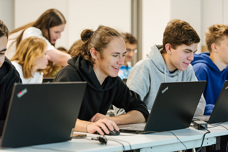 Eine Gruppe junger Menschen, am Laptop arbeitend.