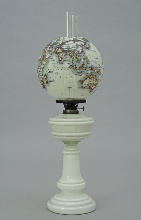 Lampe mit weißem Sockel und einem schwarz-weißen Globus als Leuchte.