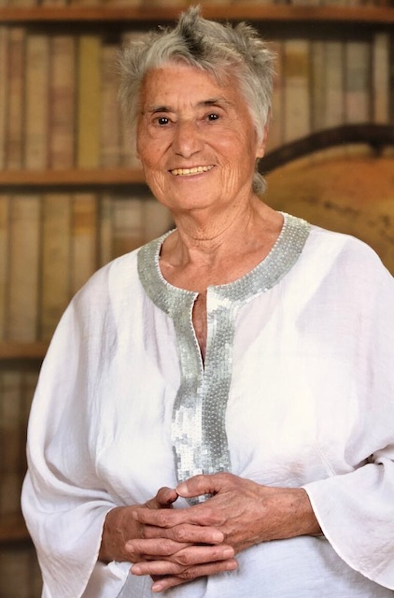 Ruth Klüger in weißer Bluse vor Bücherwand
