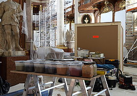 Mehrere Pulverfarben in Plastikbehältern stehen auf dem Tisch.