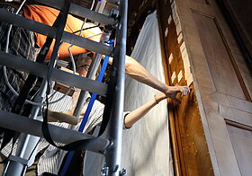 Zwei Leute auf dem Gerüst platzieren Holzblätter auf die Wand.