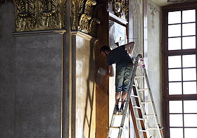 Arbeiter auf der Leiter putzt die Holzwand.