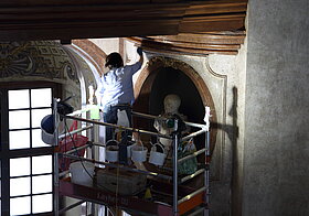Arbeiterin oben auf dem Gerüstbau putzt die Mamorwand.