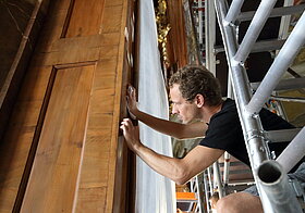 Nahaufnahme vom Arbeiter wie er die Holzwand schleift.
